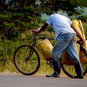 Un homme pousse un vélo qui transporte quatre bidons jaunes - Rwanda  - collection de photos clin d'oeil, catégorie portraits